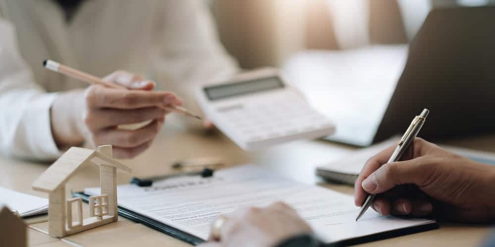 Image is of people reviewing financial documents with a calculator and house model, concept of an annulment attorney discussing financial issues related to an annulment.