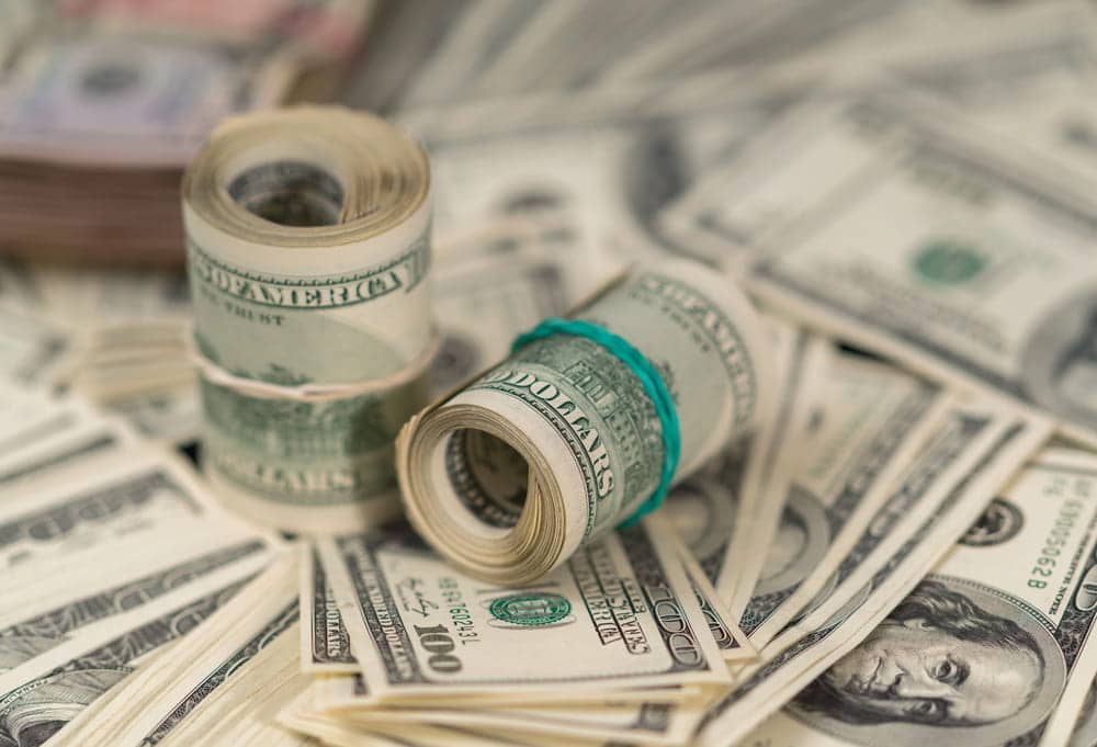 Image is of rolled dollar bills resting on stacks of cash, concept of child support modification involving financial support obligations and payment changes.