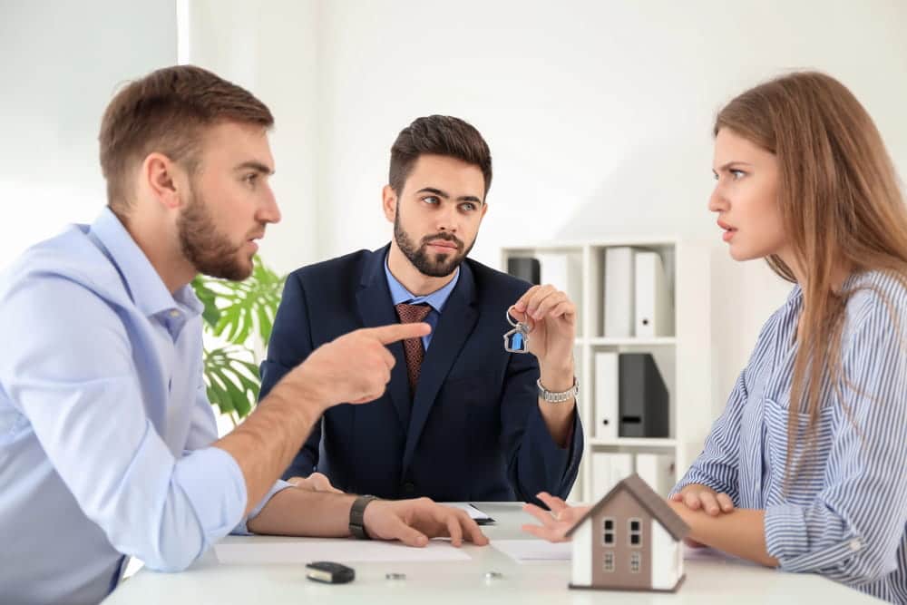 Image is of a couple speaking with a lawyer while discussing house keys and documents, concept of divorce attorney