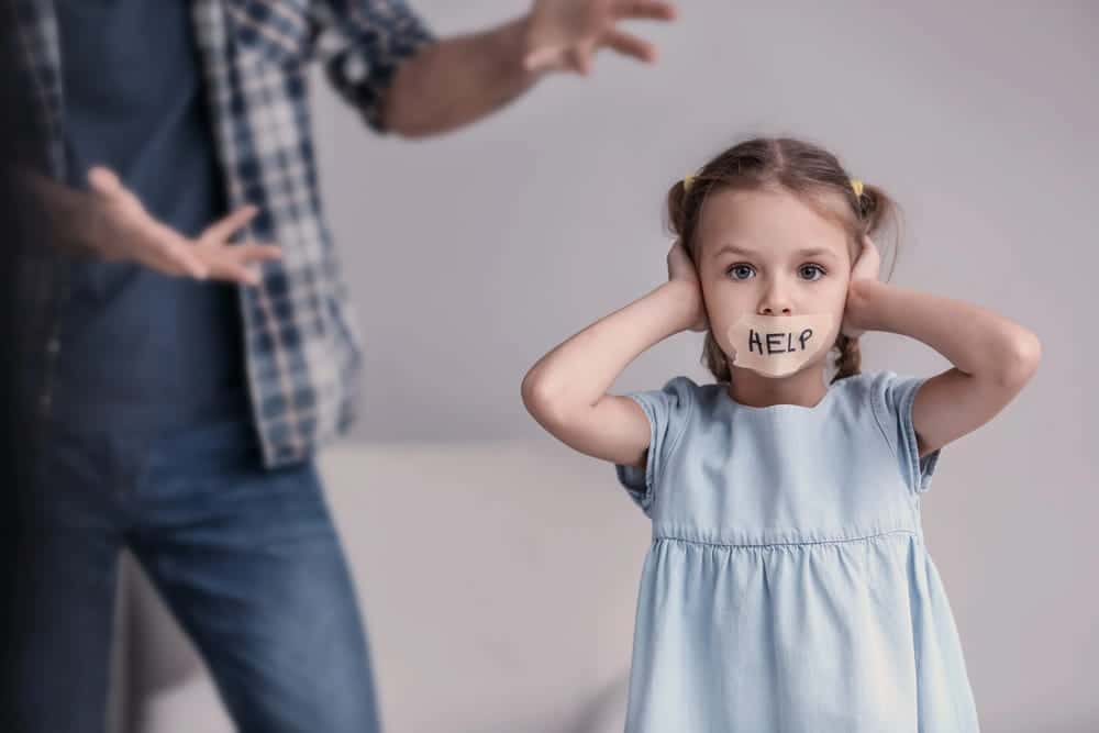 Image is of a child covering her ears while adults argue in the background, concept of an emergency custody attorney protecting a child from unsafe home conditions.