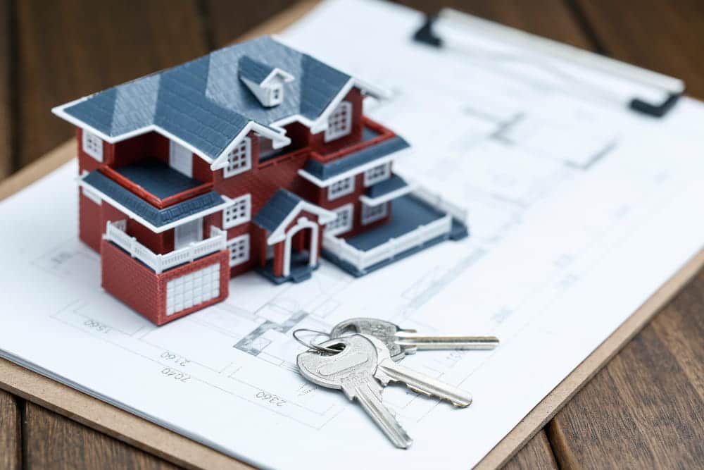 Image is of a model home and house keys resting on property plans, concept of a property division attorney handling real estate ownership and asset distribution matters.