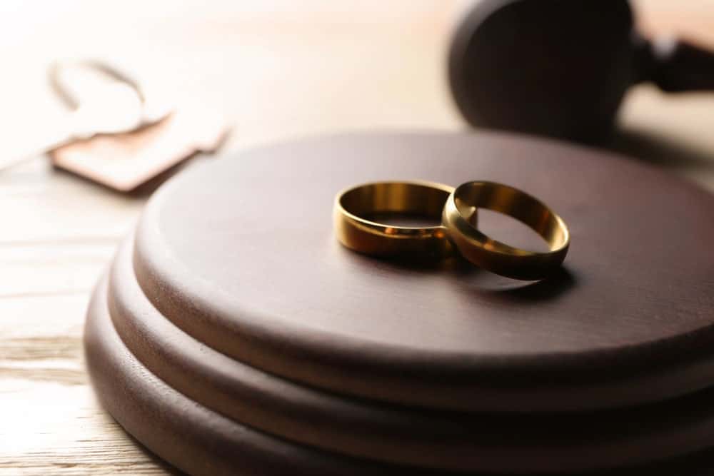 Image is of wedding rings resting on a judge's gavel, concept of a family law attorney handling divorce proceedings and marital disputes.