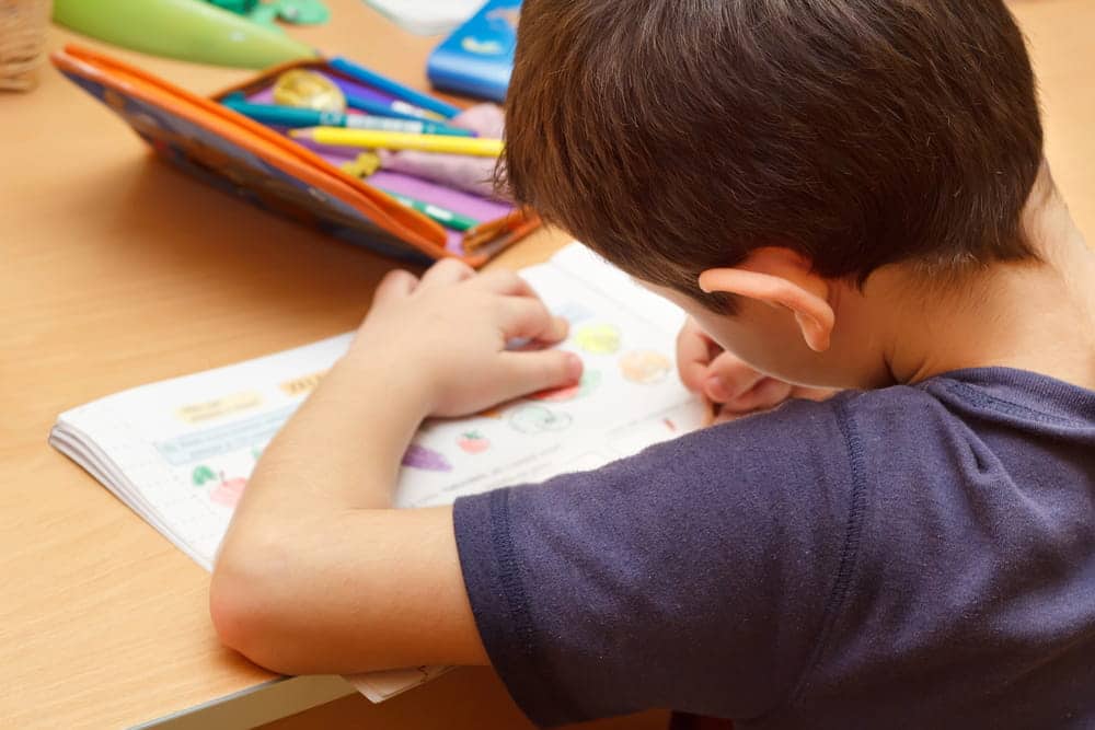 Image is of a child completing schoolwork at a desk, concept of fathers rights attorney.