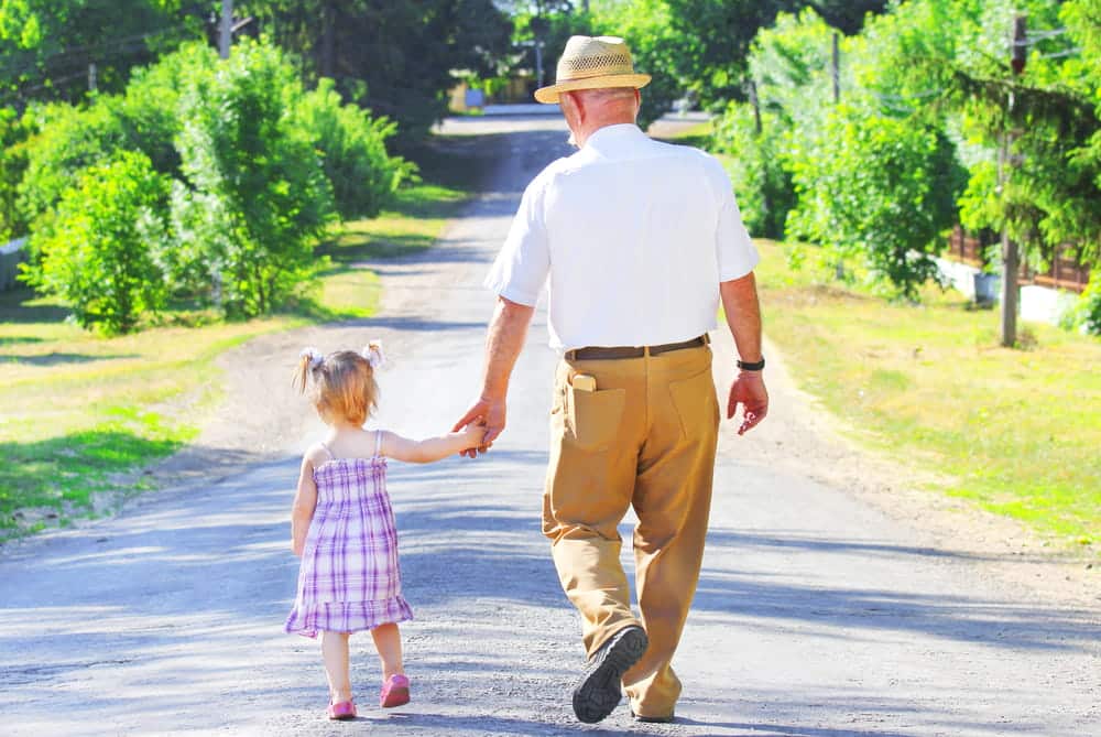 Image is of a grandparent walking while holding a child's hand outdoors, concept of a grandparents' rights attorney.