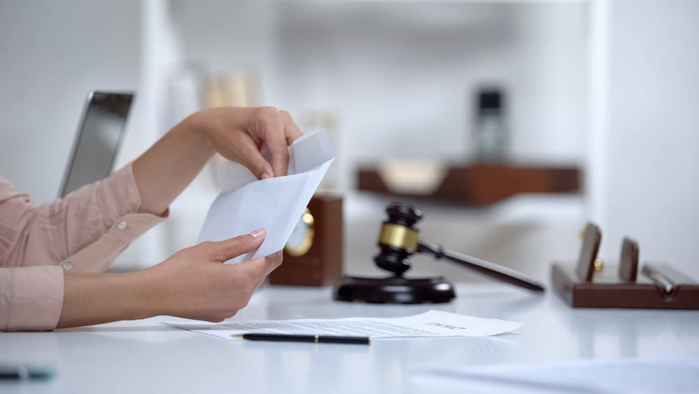 Image is of a person organizing legal documents in an attorney's office, concept of postnuptial agreement attorney.