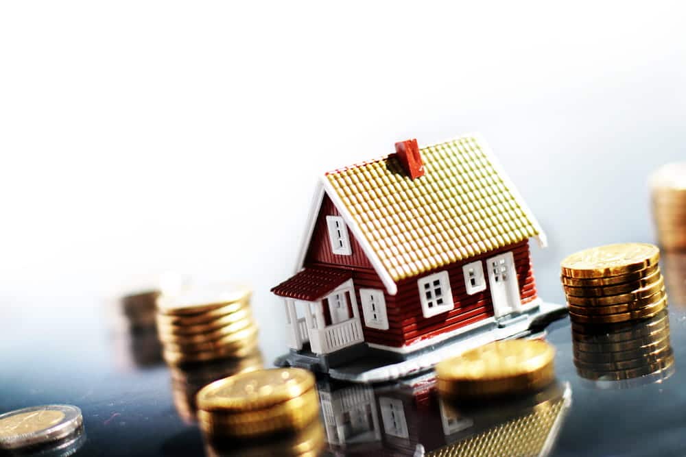Image is of a model house surrounded by stacks of coins, concept of a prenuptial agreement attorney helping couples protect financial assets and property before marriage.