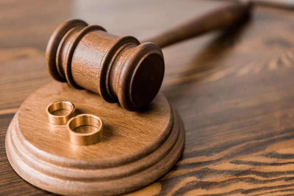 Image is of two wedding rings placed beside a judge's gavel, concept of uncontested divorce attorney