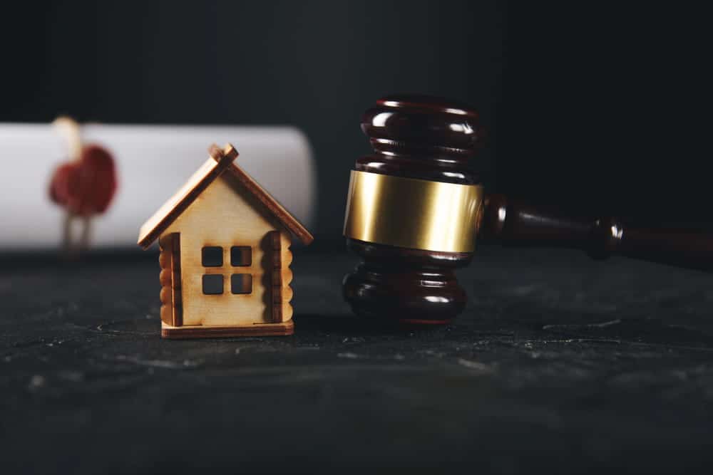 Image is of a house model beside a judge's gavel on a table, concept of uncontested divorce attorney