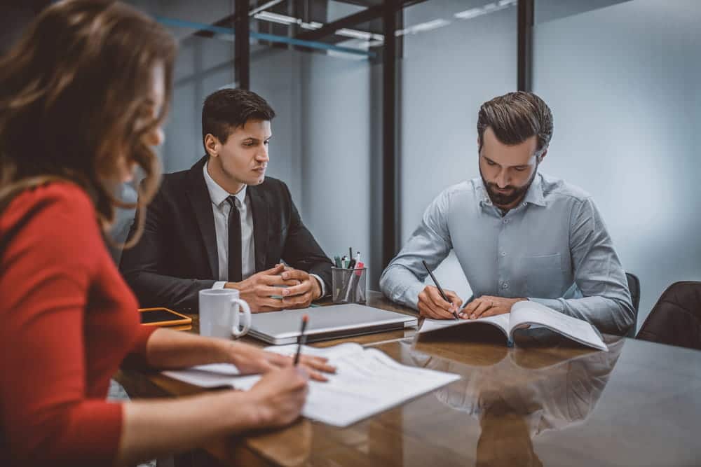 Image is of a lawyer reviewing documents with clients during a meeting, concept of divorce mediation services assisting couples in reaching mutually acceptable agreements.