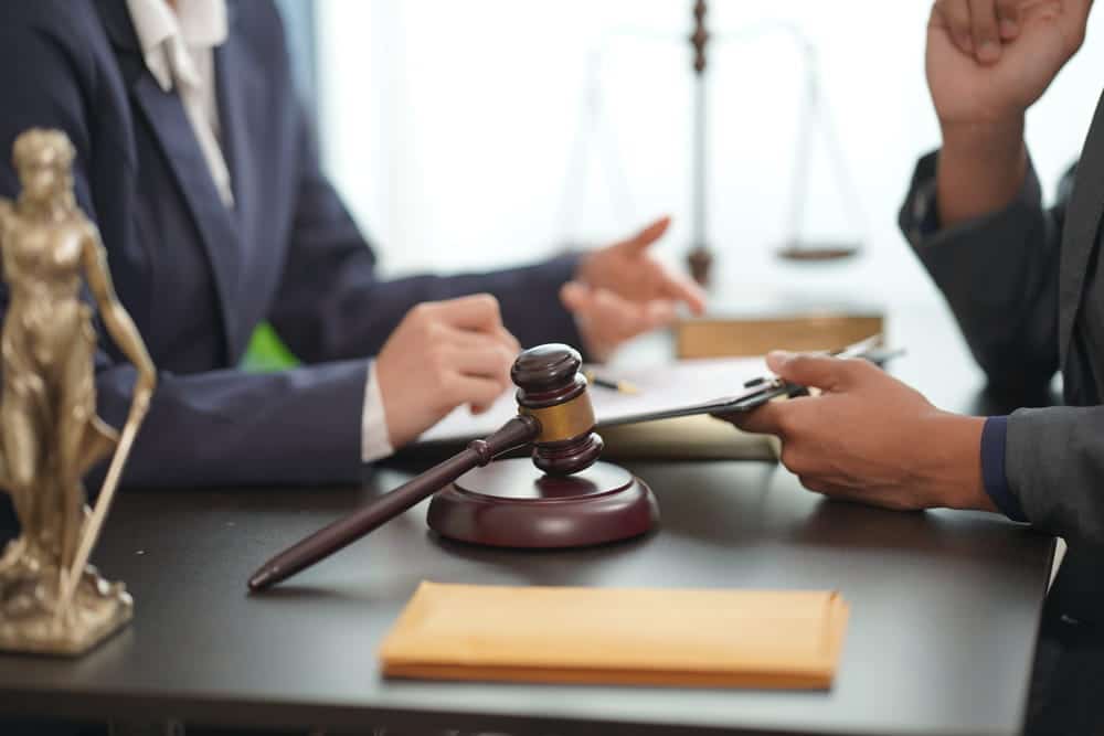 Image is of an attorney meeting with a client at a desk, concept of modifying a child custody order after changes in family circumstances.