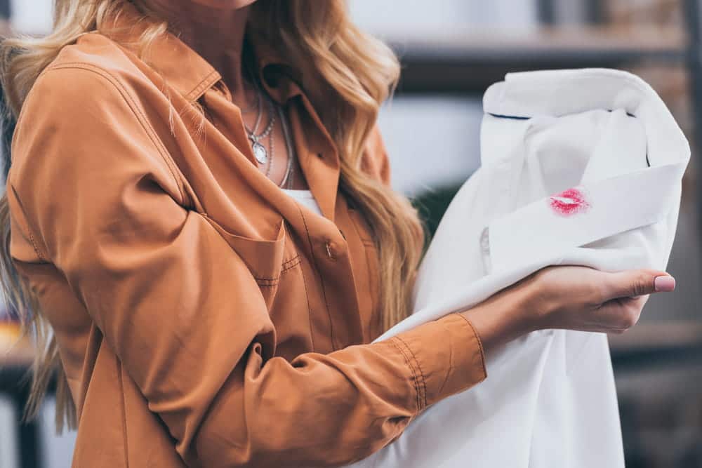 Image is of a person holding clothing with a lipstick mark, concept of a criminal conversation attorney evaluating evidence of an extramarital relationship.