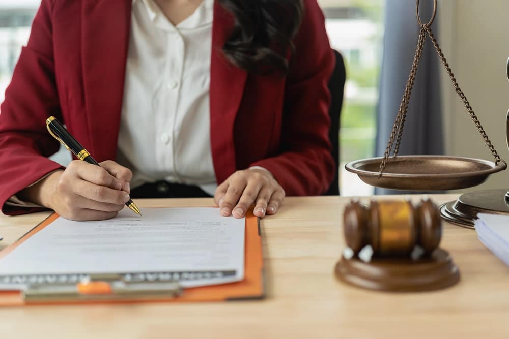 Image is of an attorney signing legal paperwork at a desk, concept of a criminal conversation attorney preparing court filings.