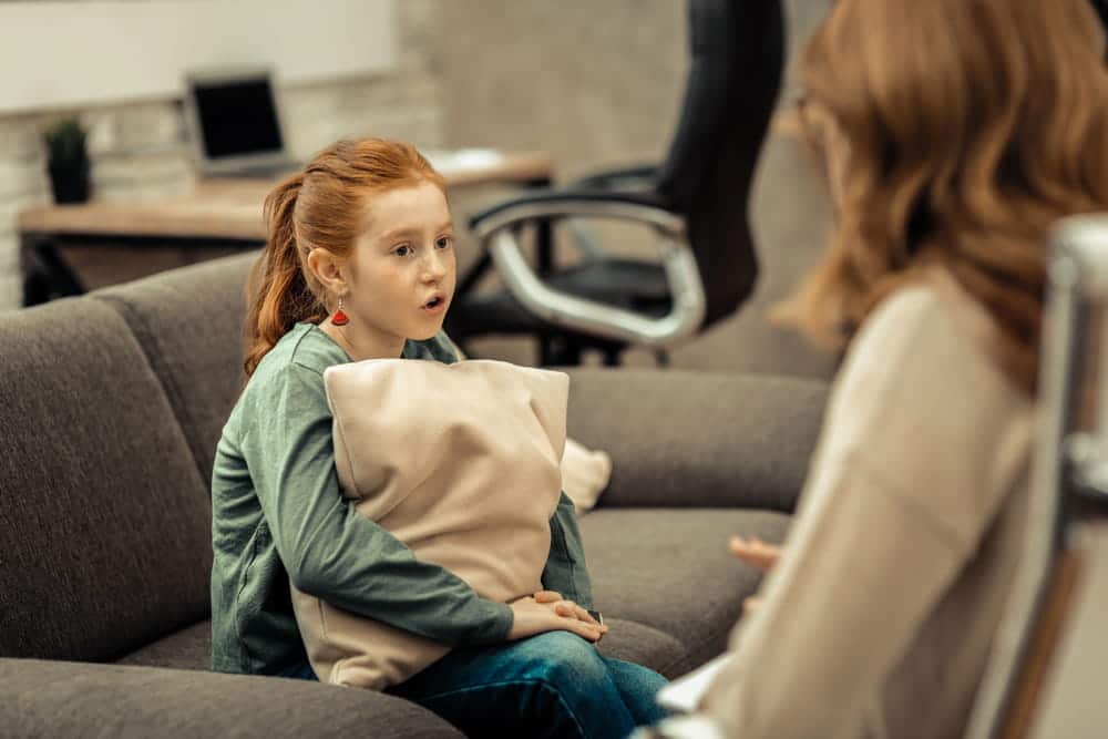 Image is of a child speaking with an adult during a family meeting, concept of parenting coordinator.