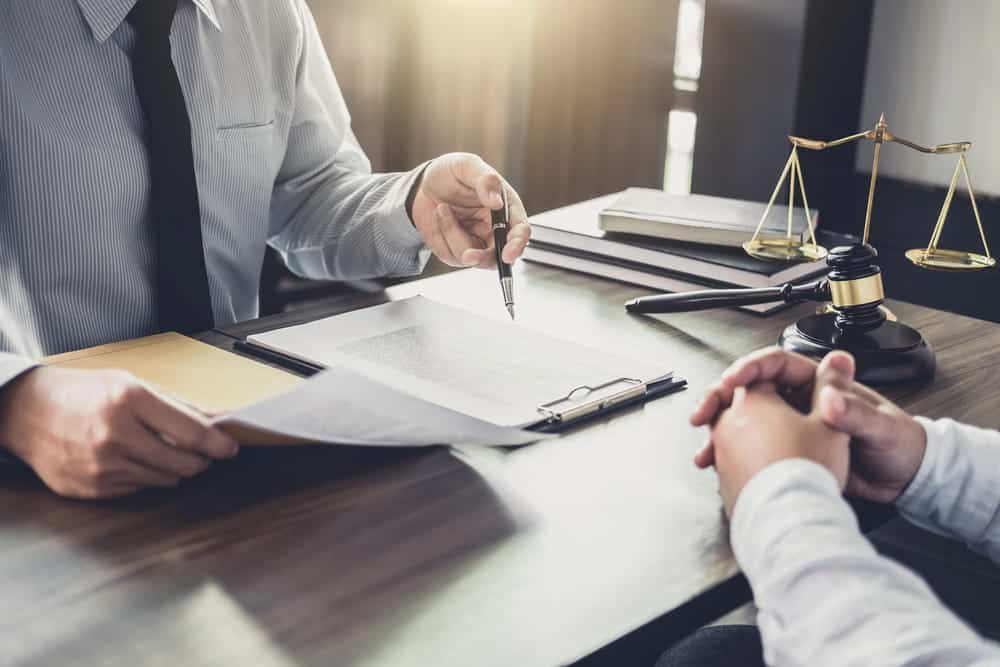 Image is of a lawyer reviewing custody documents with a client, concept of a child relocation & interstate custody attorney.
