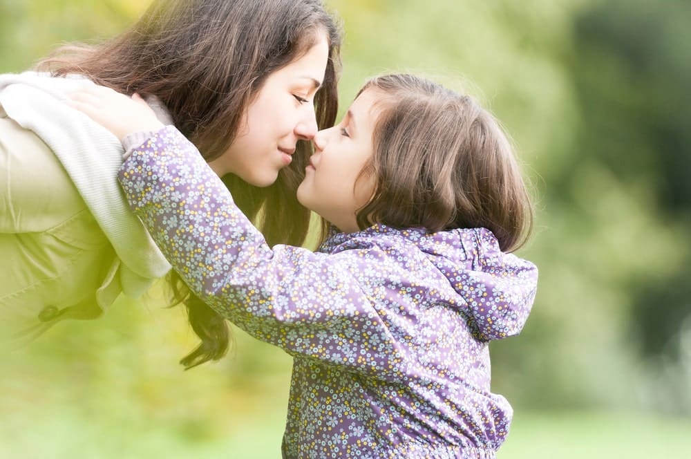 Image is of a mother embracing her young daughter outdoors, concept of a mothers' rights attorney handling custody matters
