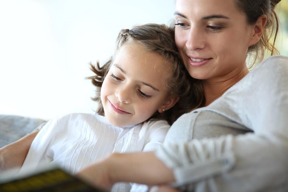 Image is of a mother reading with her daughter at home, concept of a mothers' rights attorney addressing custody concerns