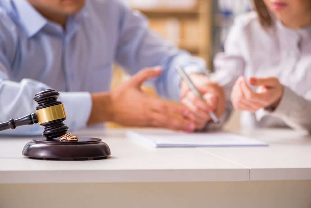 Image is of a couple reviewing legal documents beside a gavel, representing the legal process and timeline for divorce.