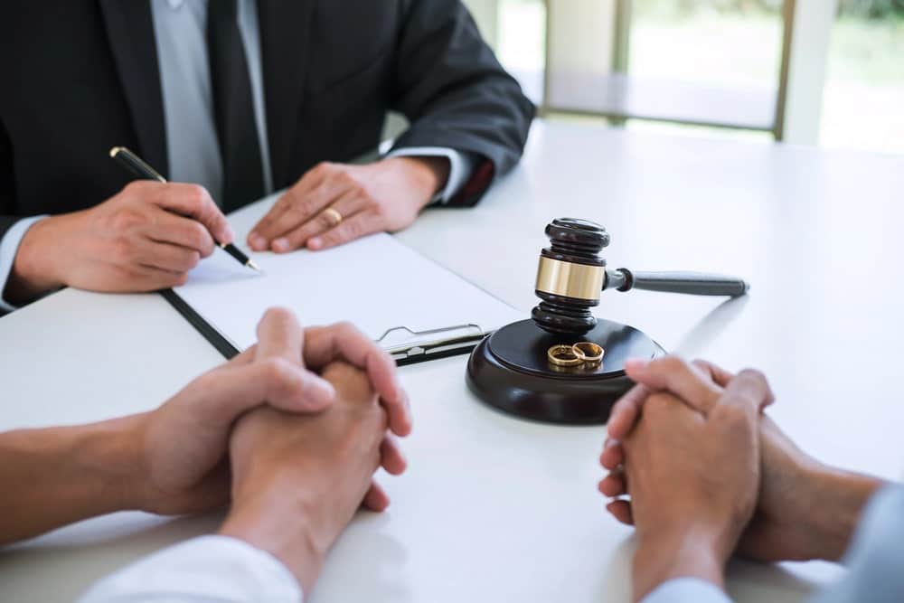 Image is of a lawyer meeting with clients and reviewing legal documents, concept of divorce in Charlotte proceedings.