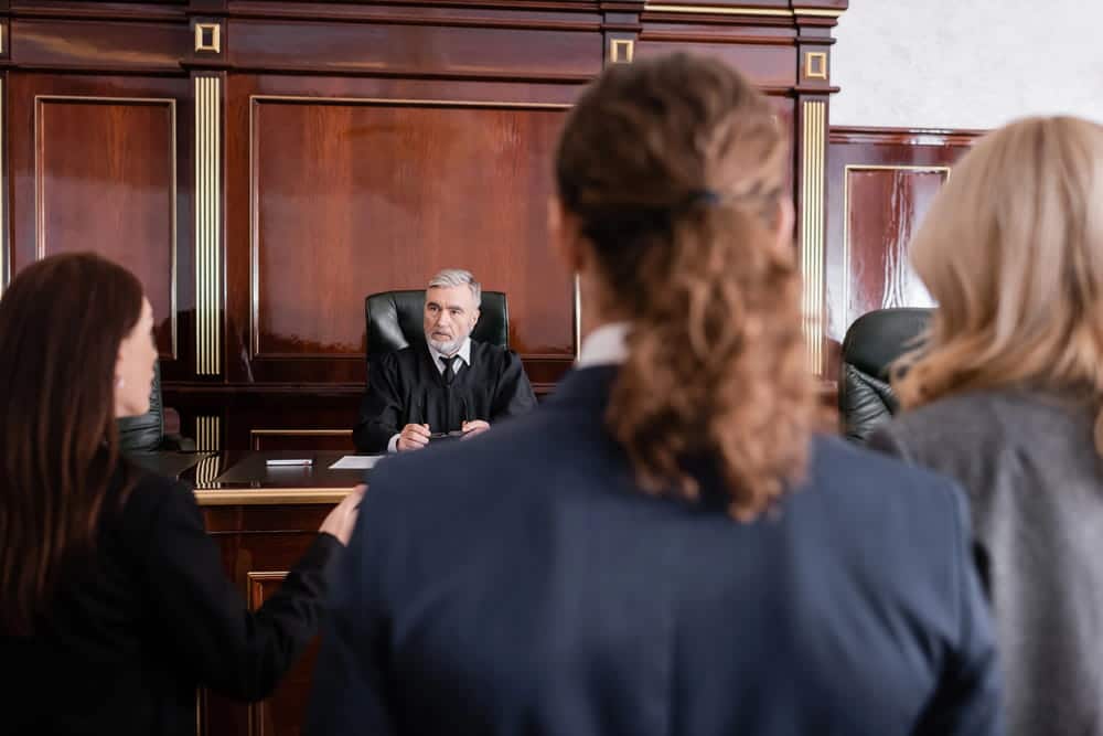 Image is of a judge hearing arguments from people in a courtroom, concept of a child custody hearing in Charlotte.