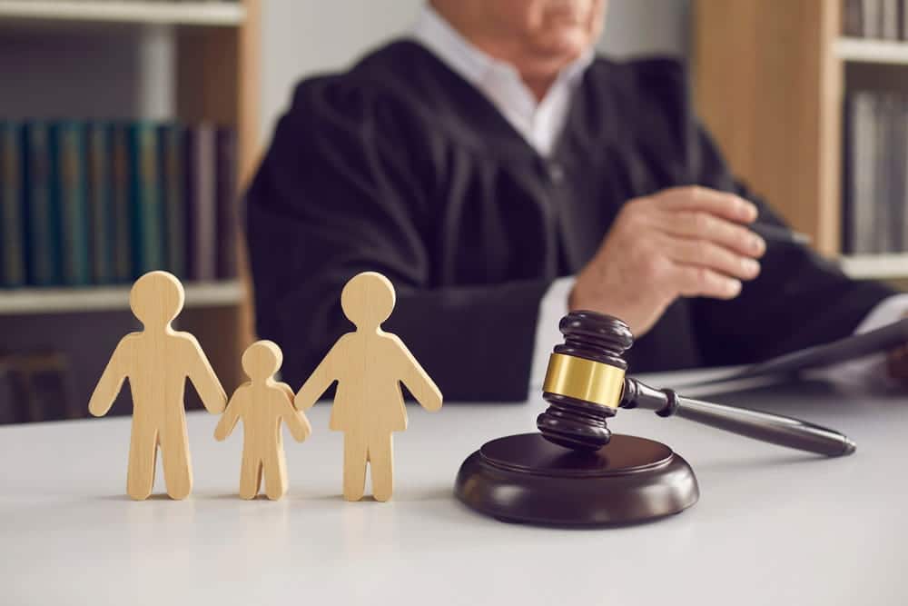 Image is of a judge with family figures and a gavel, concept of a child custody hearing in Charlotte.