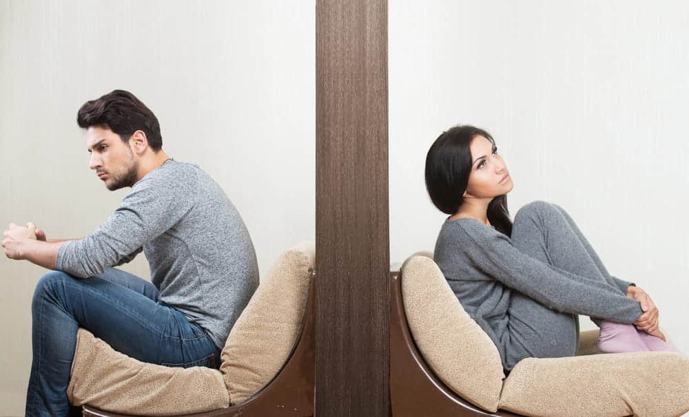 Image is of a couple sitting apart with their backs turned to each other, concept of marital separation before divorce in NC.