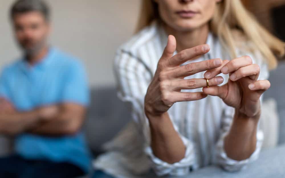 Image is of a couple sitting apart with their backs turned to each other, concept of marital separation before divorce in NC.